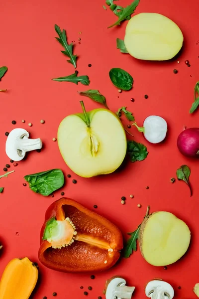 Top view of ripe fruits and vegetables near peppercorns and greens on red background - foto de stock