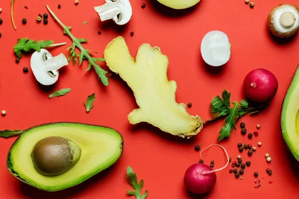 Vista superior de alimentos frescos, verdes y granos de pimienta sobre fondo rojo - foto de stock