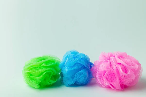 Three multicolored body puffs on grey background with copy space — Stock Photo