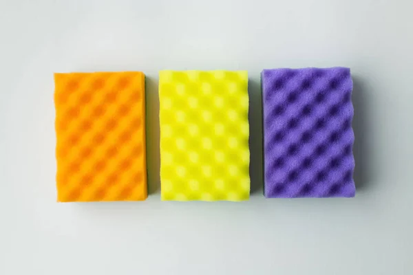 Top view of orange, yellow and purple sponges on grey background — Stock Photo