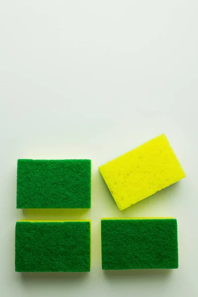 Top view of yellow and green sponge scourers on grey background — Stock Photo