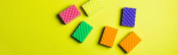 Top view of multicolored cleansing sponges on yellow background, banner — Stockfoto