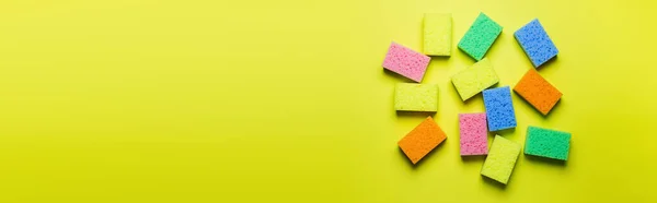 Plenty of multicolored washcloths on yellow background, top view, banner — Stock Photo
