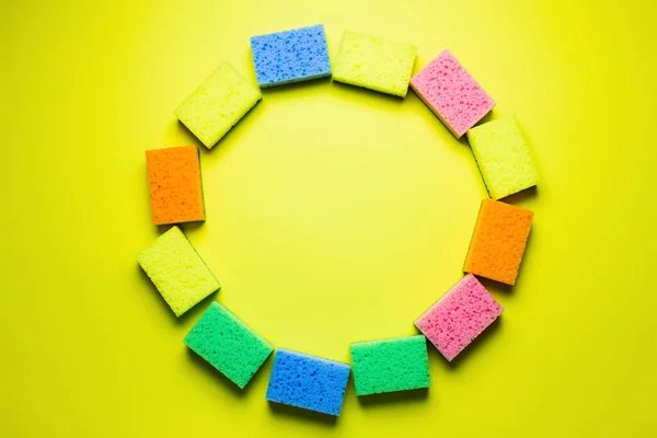 Top view of circle frame made of multicolored sponges on yellow background — стоковое фото