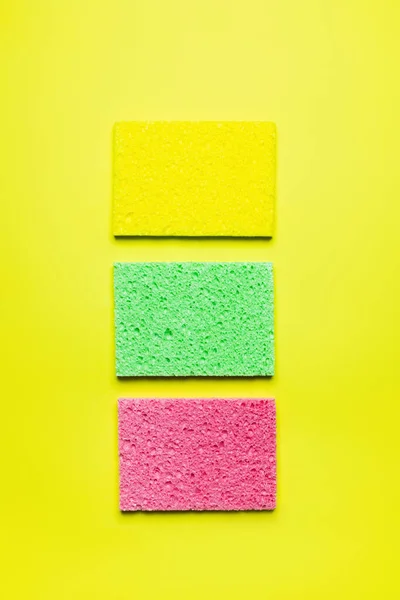 Top view of bright multicolored sponge cloths on yellow background — Stockfoto