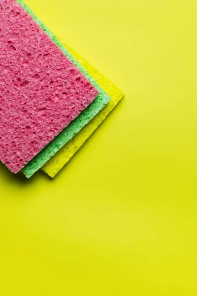Top view of bright multicolored sponge rugs on bright yellow background — Stockfoto
