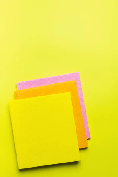 Vista dall'alto di tovaglioli di tessuto colorato su sfondo giallo brillante — Foto stock