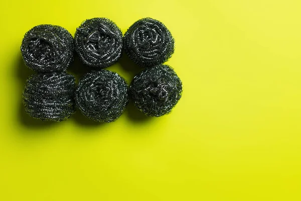 Top view of six stainless steel scrubbers on yellow background — Stock Photo