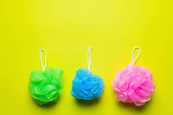 Top view of green, blue and pink body puffs on yellow background — Stock Photo