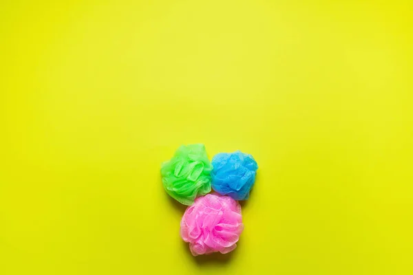 Top view of pink, blue and green body puffs on yellow background with copy space — Stock Photo