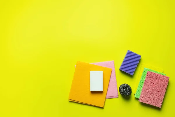 Top view of multicolored dishrags, scouring pad, sponge cloths, metal scrubber and soap on yellow background — Foto stock