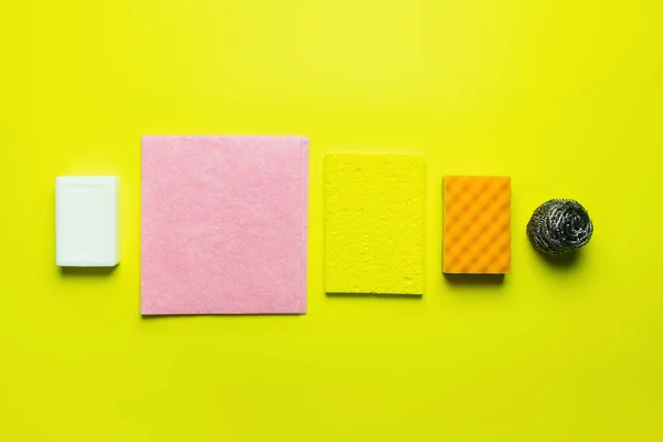 Top view of soap near dishrags, sponge scourer and steel scrubber on yellow background — Stock Photo