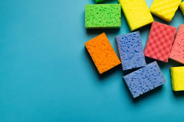 Vue de dessus des éponges nettoyantes colorées sur fond bleu — Photo de stock