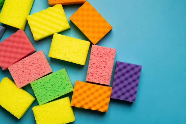 Plenty of different multicolored sponges on blue background, top view — Photo de stock