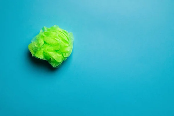 Top view of bright green exfoliating mesh body puff on blue background — Foto stock