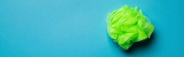 Top view of bright green body washcloth on blue background with copy space, banner — Fotografia de Stock