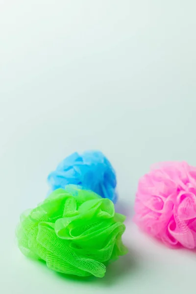 Green, pink and blue mesh washcloths on grey background with copy space — Foto stock