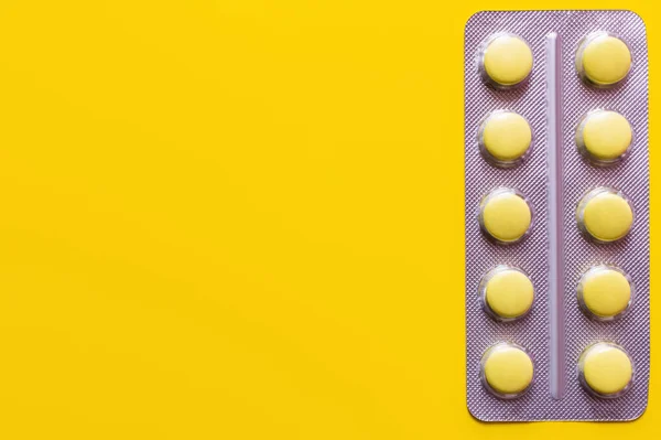 Top view of blister pack with pills isolated on yellow — Stock Photo