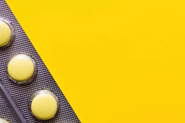 Close up of blister pack with pills isolated on yellow — стоковое фото