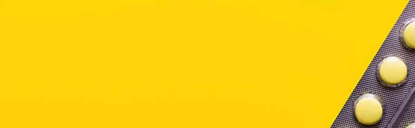 Close up of blister pack with pills isolated on yellow, banner — стоковое фото