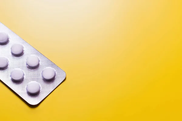 High angle view of blister pack with white pills isolated on yellow with copy space — стоковое фото
