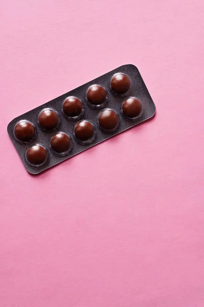 Vista superior da embalagem blister com pílulas escuras isoladas em rosa — Fotografia de Stock