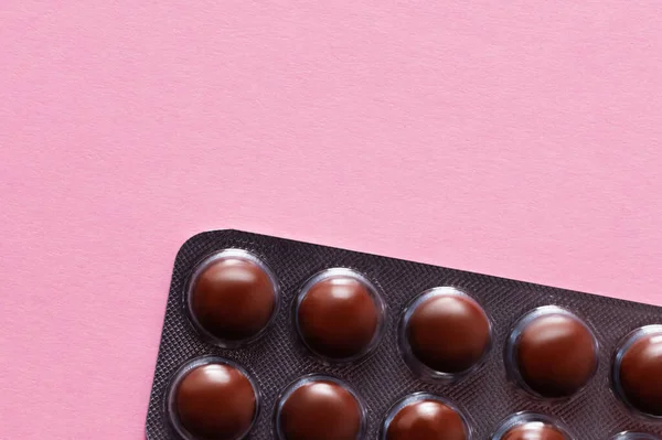 Close up view of blister pack with dark brown pills isolated on pink - foto de stock
