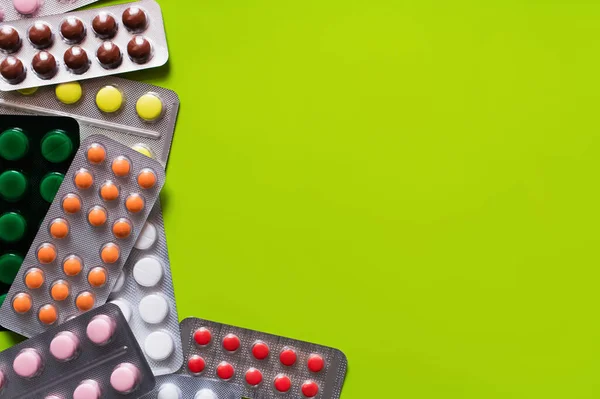 Top view of blister packs with different pills isolated on yellow-green background — стоковое фото