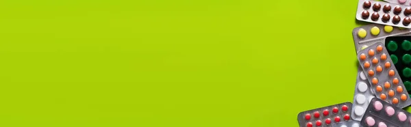 Vista superior de embalagens de blister com diferentes comprimidos isolados em verde-amarelo, banner — Fotografia de Stock
