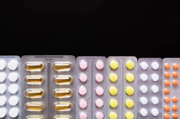 Vista dall'alto di blister con diverse pillole e capsule isolate su nero — Foto stock