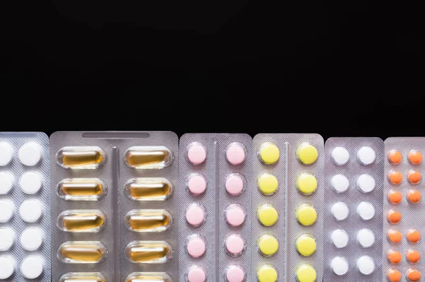 Top view of blister packs with different pills and capsules isolated on black — Stock Photo