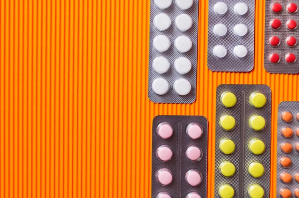 Top view of blister packs with different pills on orange textured background — Foto stock