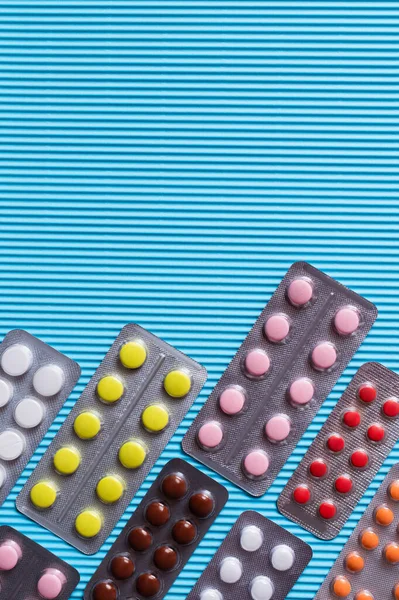 Вид зверху блістерних пакетів з різними таблетками на синьому текстурованому фоні — стокове фото