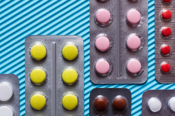 Close up view of blister packs with different pills on blue textured background - foto de stock