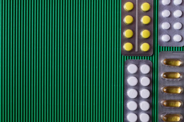 Top view of blister packs with different pills and capsules on textured green background — Foto stock