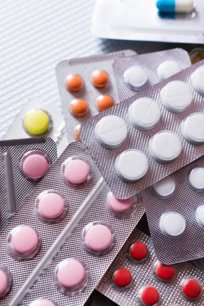 Top view of blister packs with different colorful pills on white textured background — Stock Photo