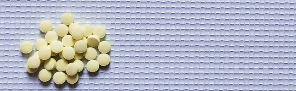 Top view of pile with yellow round shape pills on white textured background, banner — Stockfoto