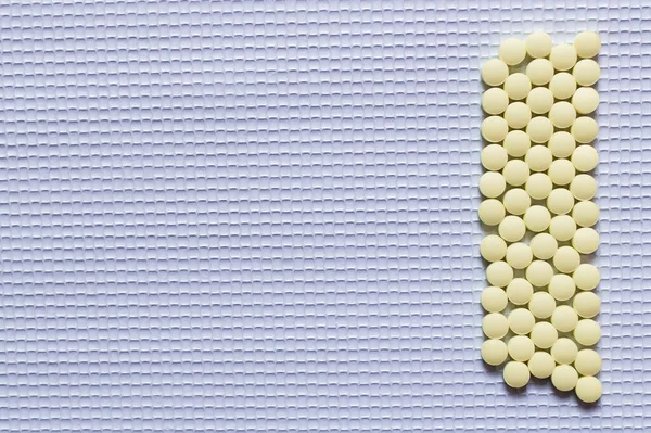 Flat lay of yellow round shape medication on white textured background — Foto stock
