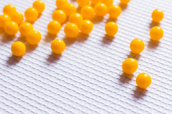 Close up view of yellow round shape vitamin pills on white textured background — стоковое фото