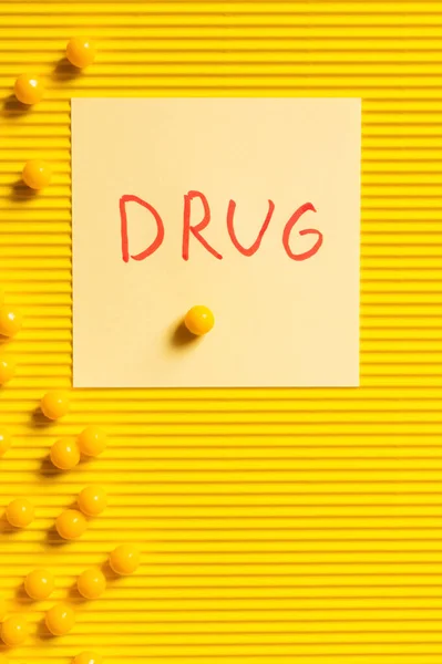 Top view of round shape medication near paper note with drug lettering on yellow textured background — Stock Photo