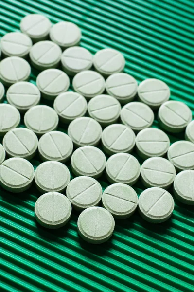 Close up view of round shape medication on textured green background - foto de stock