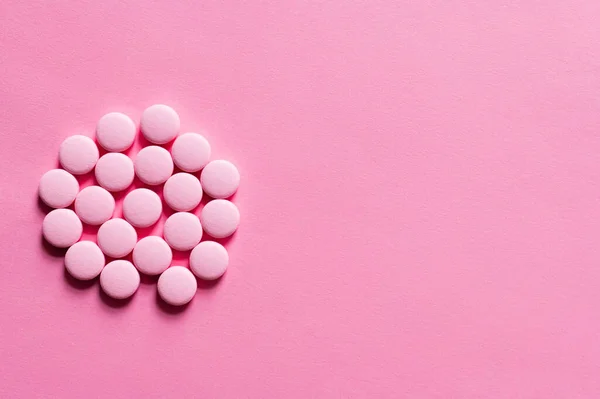 Vue de dessus de pile avec des pilules en forme ronde sur fond rose — Photo de stock