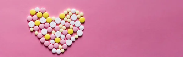 Piatto lay vista di diverse pillole rotonde a forma di cuore su sfondo rosa, banner — Foto stock
