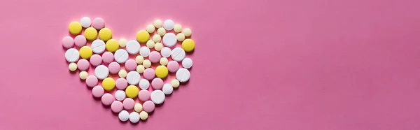 Flat lay view of different round pills in shape of heart on pink background, banner — стоковое фото
