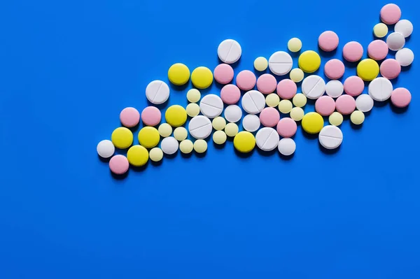 Flat lay view of different round shape pills on blue background - foto de stock