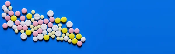 Flat lay view of different round shape pills on blue background, banner — стоковое фото