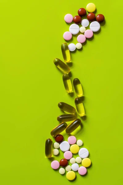 Flat lay of different colorful pills and jelly capsules on green background — Foto stock