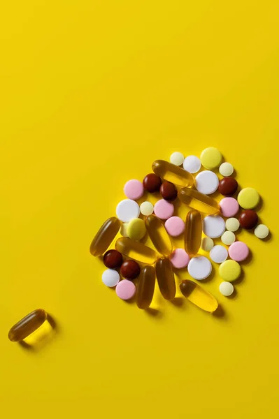 Vista dall'alto di pillole colorate e capsule di gelatina su sfondo giallo — Foto stock