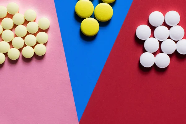 Top view of round shape white and yellow pills on colorful background - foto de stock