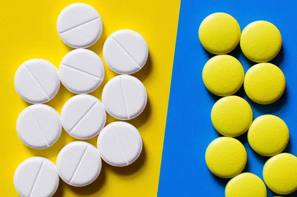 Vista dall'alto di pillole di forma rotonda su sfondo blu e giallo — Foto stock